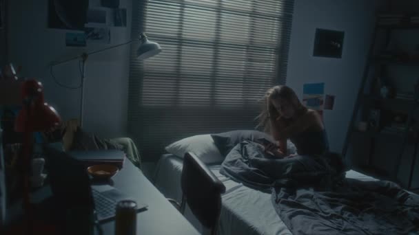 眠れない夜に寝室に一人で座っている若い女性のハイアングルショット スマートフォンを使用して サイバーいじめやドゥームスクロールのために悲しみを感じます — ストック動画