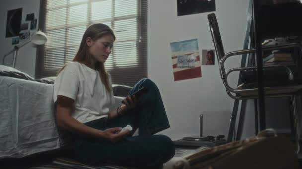 忧心忡忡的女孩坐在卧室的地板上 一边打电话一边拿药一边想着自杀 — 图库视频影像