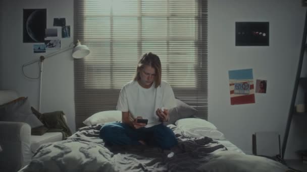 自宅でベッドに座り 錠剤やスマートフォンを持ち 自殺を考えている少女 — ストック動画