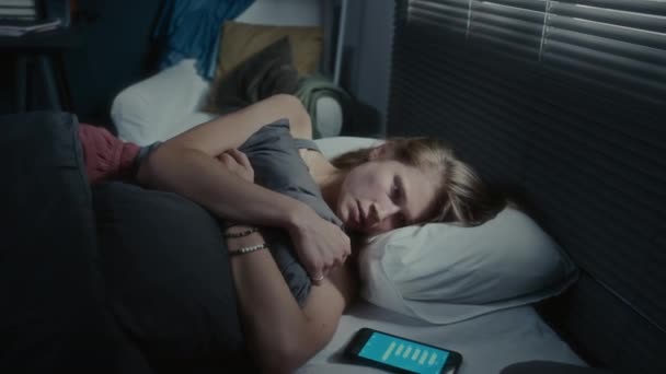 女孩躺在床边智能手机旁边 屏幕上显示短信 晚上抱着枕头哭泣 — 图库视频影像