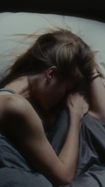 Yatakta uzanmış, gergin bir şekilde saçlarını tutup ağlayan bir kız resmi.
