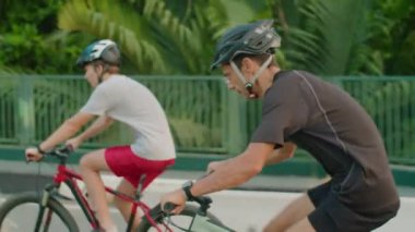 Kenar manzaralı, sporcu bir adam ve oğlunun şehir yolunda bisiklet sürerken çekilmiş görüntüleri.
