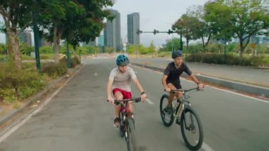 Baba ve oğlunun yaz günü birlikte bisiklet sürerken spor kıyafetlerini giydikleri ön manzara.