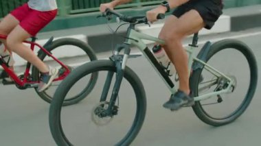 Yaz günü oğluyla bisiklet sürerken kasklı bir sporcunun yol boyunca bisiklet sürüşünü çek.