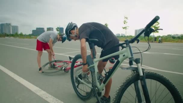 男性のサイクリストは 彼の息子が都市道路の後ろにタイヤをポンピングしながら再インストールするためにバイクホイールを取り外します — ストック動画