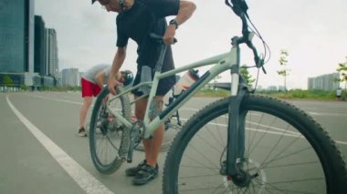 Oğlu şehir yolunda lastiği pompayla şişirirken babası bisiklet tekerleğini yeniden takıyor.