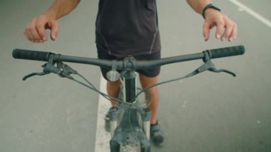 Spor giyim mağazasında bisiklet sürerken gidonu tutan erkek bisikletçinin görüntüsü.