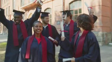 Mezuniyet töreninden sonra diplomalı ve cübbeli bir grup çok kültürlü öğrenciyi takip ediyoruz.