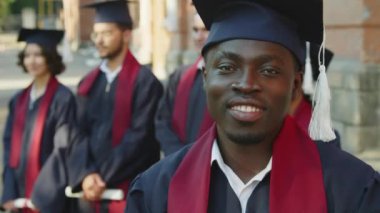 Mezuniyet töreninde kameraya bakan gururlu Afrikalı Amerikalı öğrencinin portresini yakından çek.