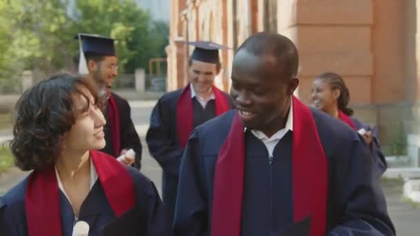 Отслеживание Съемки Молодых Людей Университетских Платьях Шляпах Разговаривающих Друг Другом — стоковое видео