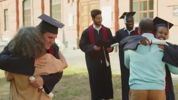 Mediana Posibilidad Largo Diversos Estudiantes Batas Sombreros Abrazando Sus Padres — Vídeos de Stock