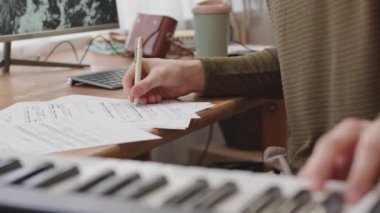 Erkek müzisyenin notaları kağıda yazıp evde müzik yaratırken sentezleyici çaldığı sahneler.