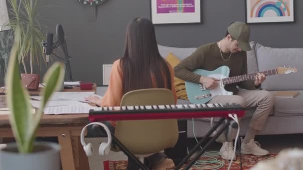 Junger Mann Sitzt Auf Sofa Wohnzimmer Und Spielt Gitarre Während — Stockvideo