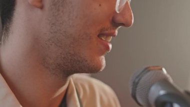 Stüdyo provası sırasında adamın müzik çalarken ve mikrofona şarkı söylerken yakın plan çekimleri.