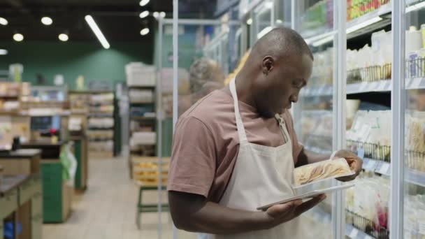 프론에서 슈퍼마켓 노동자의 냉장고 통로에 서있는 준비가 제품의 데이터를 확인하고 — 비디오