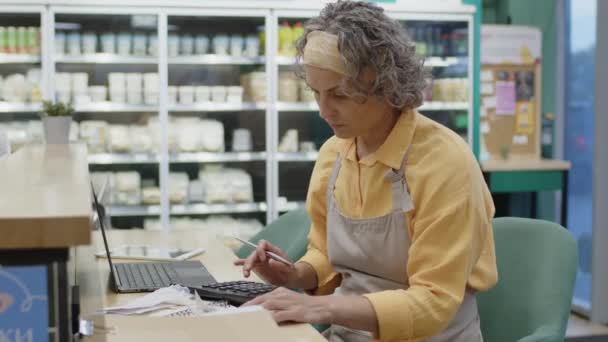 Średnie Ujęcie Białej Kobiety Pracującej Supermarkecie Siedzącej Przy Laptopie Przeglądającej — Wideo stockowe