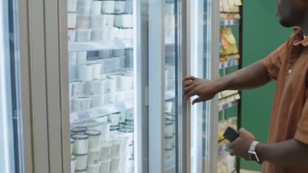 Medium Shot Young Black Man Opening Supermarket Fridge Taking Out — Stock Video