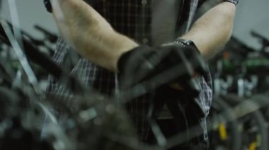 Garajda bisikleti tamir etmeden önce eldiven takan bir tamirci görüntüsü.