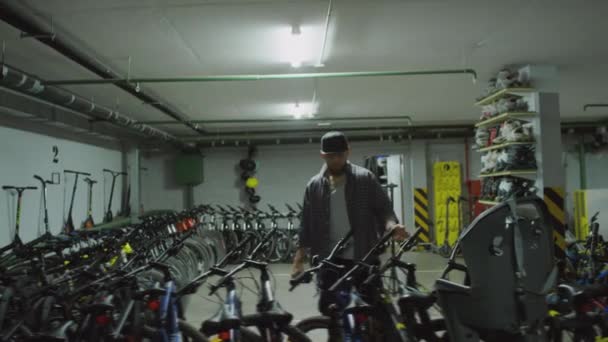 Młody Człowiek Sprawdzający Rowery Stojące Rzędzie Podczas Pracy Sklepie Rowerowym — Wideo stockowe