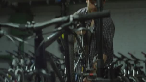自転車の車輪を取り外し 修理工場で働いている間歩いている人のハンドヘルドカメラのショット — ストック動画