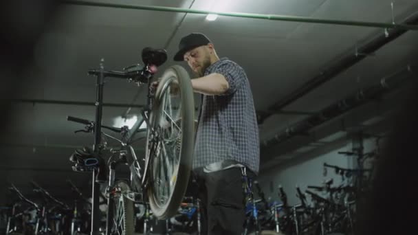 自転車の機械回転ホイール 交換後に点検し 修理工場で作業中の布で手を拭く — ストック動画