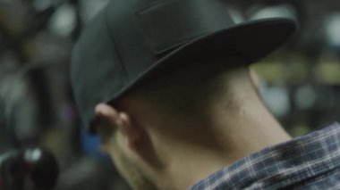 Erkek teknisyenin kulaklık takıp portatif kasetçalara müzik açarken iş saatinde bisiklet tamirhanesinde mola verirken yakın plan çekimleri.