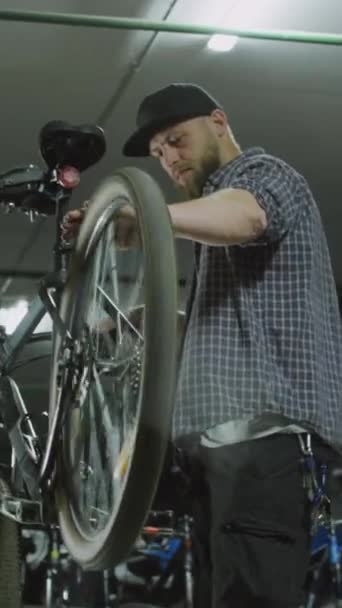 修理工場で作業中の布で機械回転バイクホイールとクリーニングハンドの垂直ショット — ストック動画