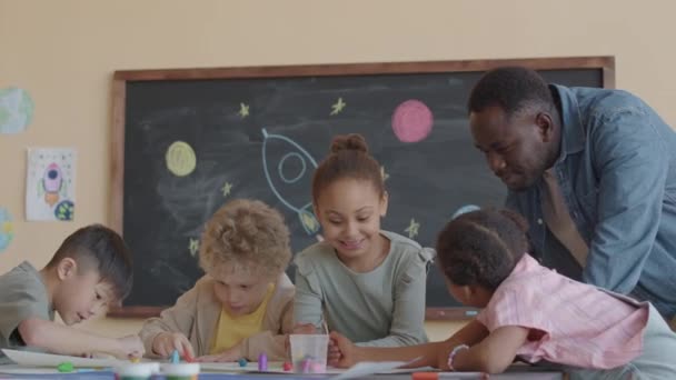 Professor Afro Americano Sorrindo Conversando Com Crianças Multi Étnicas Desenhando — Vídeo de Stock