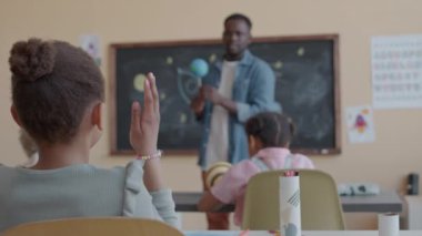 Astronomi dersi sırasında sınıftaki küçük Afrikalı Amerikalı kızın el ele tutuşup soru sormasının seçmeli odak noktası.