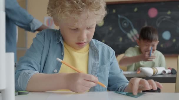 小学生在小学上手工操作课时 一个金发碧眼的小孩用铅笔在纸上打分 — 图库视频影像