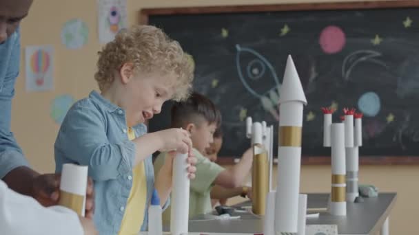 Маленький Блондин Строит Бумажную Ракету Помощью Афроамериканского Учителя Время Выполнения — стоковое видео