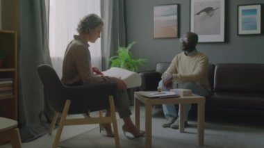 Yetişkin kadın somnolojistin ortopedik yastık verdiği ve klinikteki tıbbi randevu sırasında Afrikalı Amerikalı hastaya uyku hijyeni hakkında konuştuğu görüntüyü yakınlaştır.