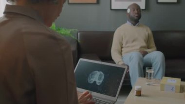 Dizüstü bilgisayarda yazan ve klinikteki uyku testi sırasında ekranda görülen hasta beyninin aktivitesini inceleyen kadın doktor.