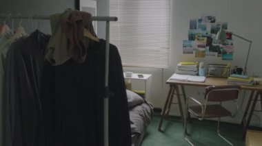 Yurt odasındaki dağınık yatağın görüntüsünü büyüt. Sabahları giysi askısı ve masası var, kimse yok.