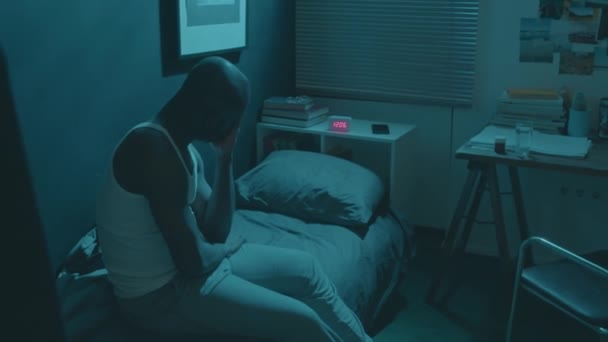 眠れないアフリカ系アメリカ人の男がベッドに座って不眠症に苦しみ 彼の顔をこすり 自宅で夜間に疲れを感じる — ストック動画