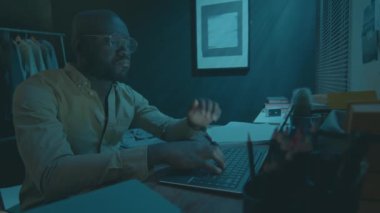 Çok çalışan Afrikalı Amerikalı adam bilgisayarını kapatıp geceleri karanlık bir odada uyuyakalıyor.