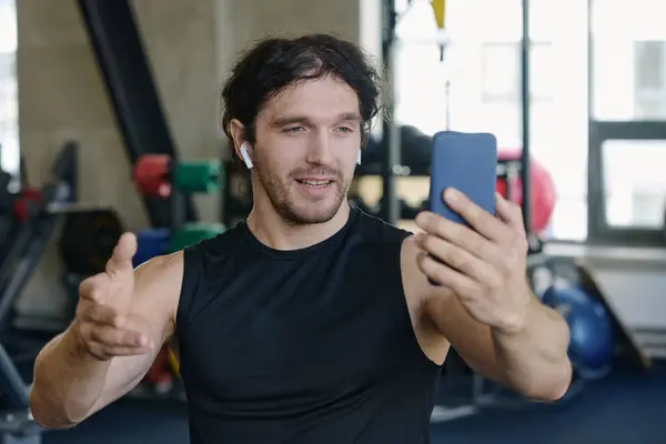 Medium closeup of young caucasian fitness blogger filming himself on his smartphone at gym