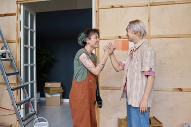 Mutlu kızlar el sıkışıyor, gelecekteki daire tasarımları için renk seçiyorlar.