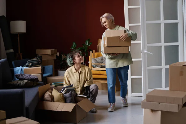 Lesbian couple moving to their new apartment, they carrying and unpacking cardboard boxes together