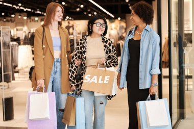 Çok ırklı genç kızlar alışveriş merkezinin yakınında sohbet ediyorlar.