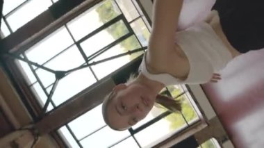 Geniş çatı katı dans sınıfında dans eden tutkulu genç bayan modern dansçının dikey açısı. Büyük pencereli.