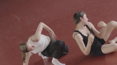 Yukarıdan iki kadın dansçının geniş dans stüdyosundaki kırmızı parke zemininde şehvetli çağdaş dans gösterileri.