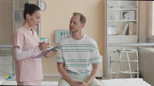 Fisioterapeuta Femenina Matorrales Sujetando Portapapeles Conversando Con Paciente Masculino Durante — Vídeos de Stock