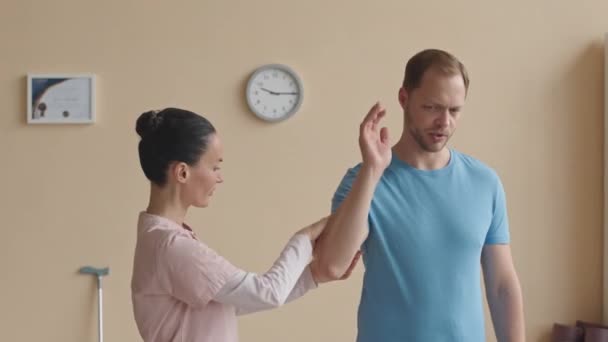 女性カイロプラクター 男性患者の腕を曲げ 診療所の医学の仕事日の間に筋肉をパルスする — ストック動画