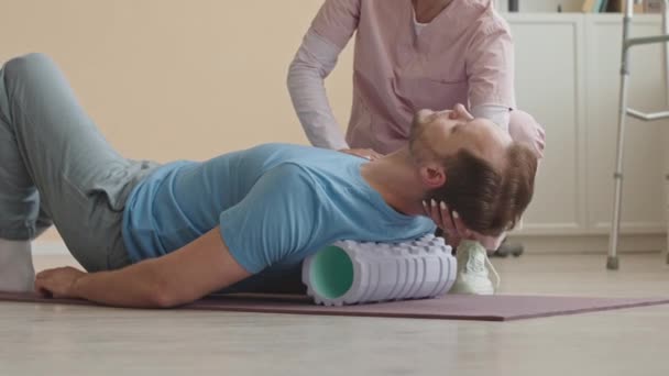 Vrouwelijke Fysiotherapeut Helpt Mannelijke Patiënt Schuim Rollen Zijn Rug Spieren — Stockvideo