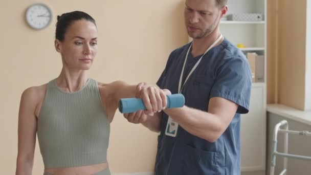 Mężczyzna Fizjoterapeuta Pomaga Kobieta Pacjent Robi Hantle Przodu Podnieść Podczas — Wideo stockowe