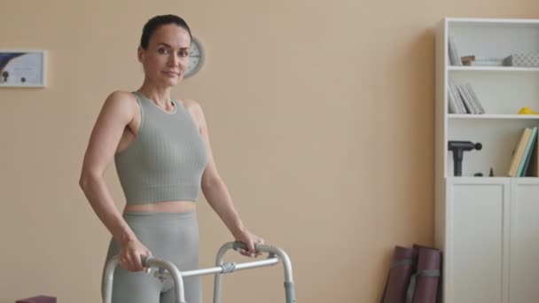 Średnie Ujęcie Kobiety Odzieży Sportowej Stojącej Ramą Spacerową Klinice Fizjoterapii — Wideo stockowe