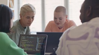 Genç çok ırklı üniversite arkadaşları dizüstü bilgisayarlara programlama kodları yazıyorlar ve bilgisayar bilimi dersinde grup projelerini tartışıyorlar.