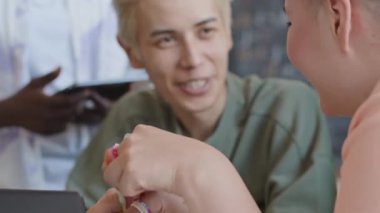 Seçici odak noktası, bilgisayar bilimi dersi sırasında sınıf arkadaşıyla sohbet eden ve sınıfta birlikte otururken gülümseyen neşeli üniversiteli kız.