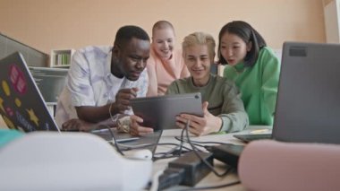 Üniversitedeki programlama dersi sırasında grup projesi üzerinde çalışırken dijital tablet hakkında veri tartışan Z gen grubundan çeşitli öğrenciler